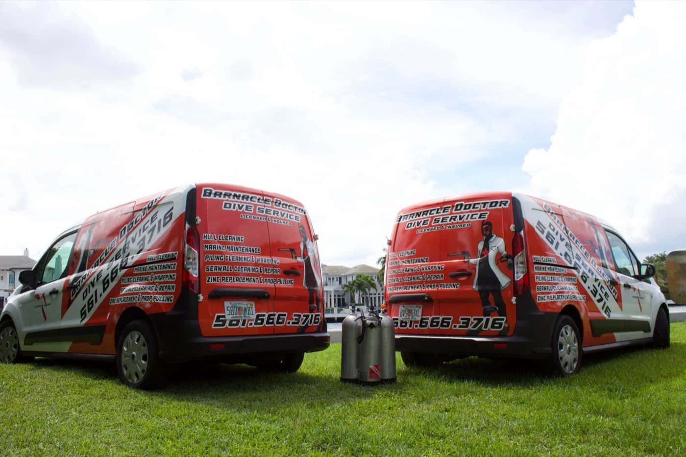 Two Barnacle Doctor service vans parked by the water