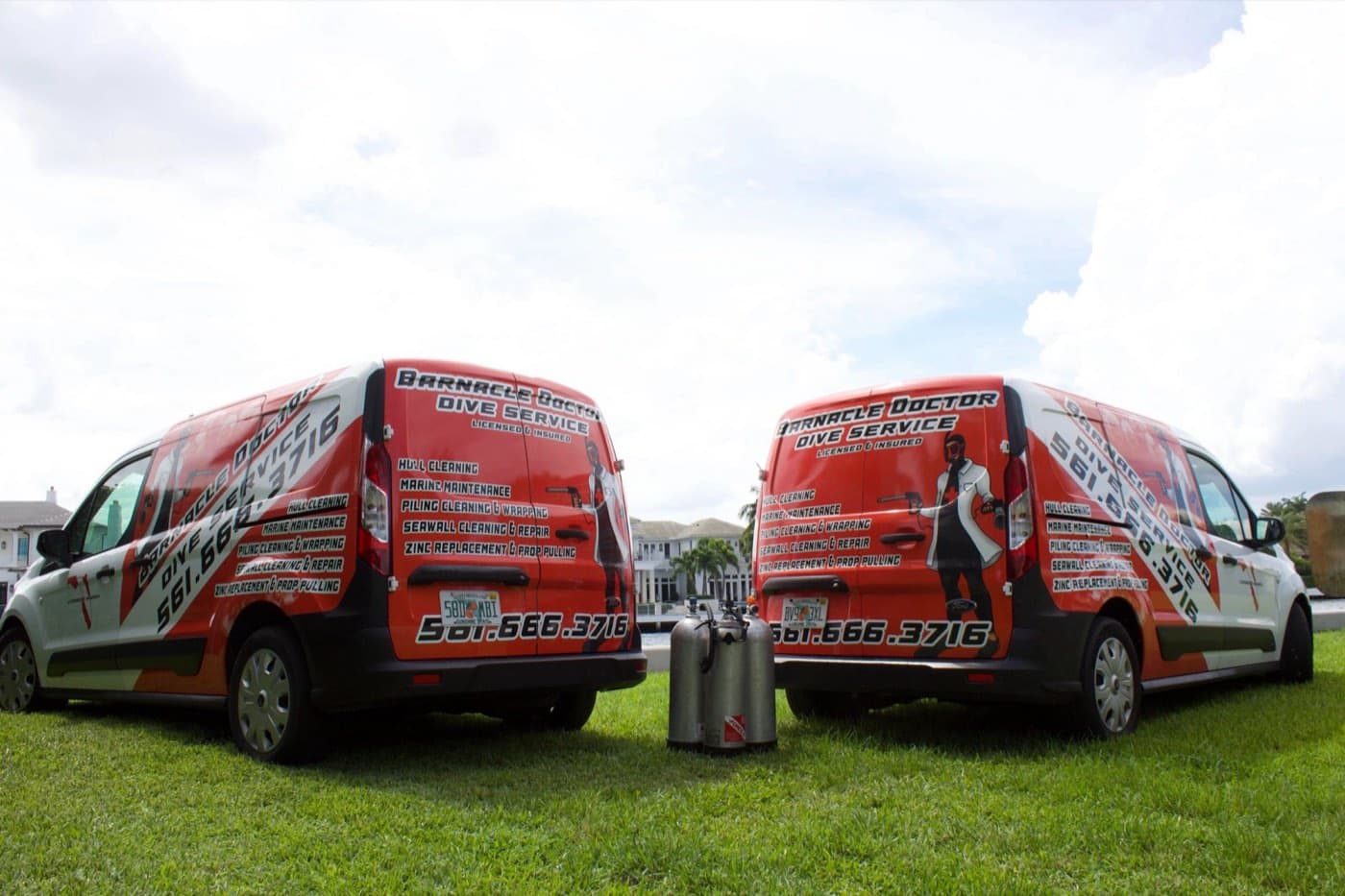 Two Barnacle Doctor service vans parked by the water